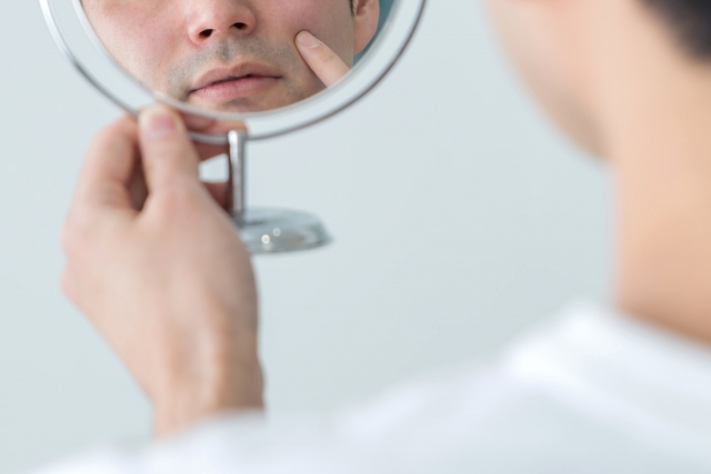 鏡で皮膚を確認する男性